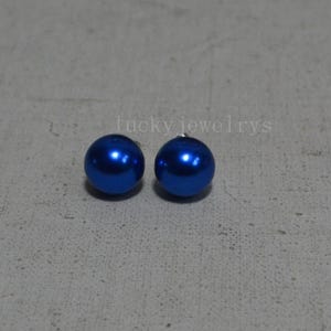 May include: Two cobalt blue, round stud earrings. The earrings have a glossy finish and are set against a neutral gray background. The text "lucky jewelrys" is visible in the background.