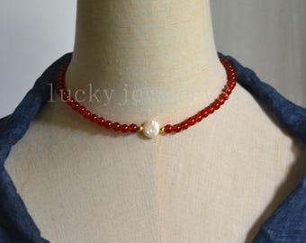 May include: A red beaded necklace with a single white pearl pendant. The necklace is displayed on a mannequin. The text "lucky jew" is visible on the left side of the image.