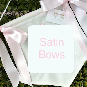May include: White fabric banner with pink satin bows and the text "Satin Bows" in pink lettering.