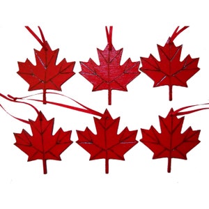 Peut inclure: Six ornements en forme de feuille d'érable en bois rouge avec des rubans rouges. Les feuilles sont peintes en rouge et ont une texture de grain de bois.