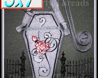 May include: A white fabric coffin-shaped pouch with a black embroidered rose and swirls. The pouch is 5x7 inches and is attached to a grey fabric strap.
