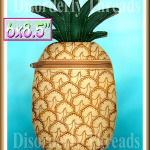 Puede incluir: Una bolsa con cremallera en forma de piña amarilla con una parte superior de fieltro verde. La bolsa mide 15,24 x 21,59 cm y tiene una cremallera marrón.