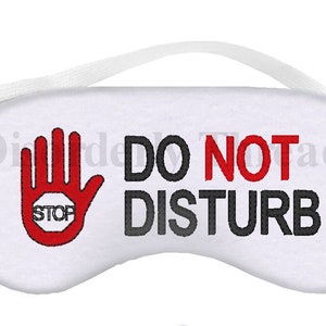 May include: White sleep mask with a red hand with a stop sign and the text "DO NOT DISTURB" in black.