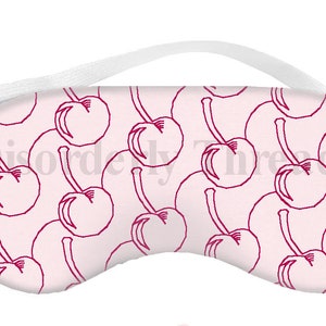 Può includere: Una maschera per dormire rosa con un motivo ripetuto di ciliegie rosse. La maschera ha un elastico bianco.