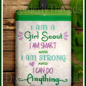 Puede incluir: Una bolsa blanca con cremallera, con la parte superior verde y un dise&ntilde;o bordado en verde y morado que dice "Soy una Girl Scout, soy inteligente y soy fuerte y puedo hacer cualquier cosa".