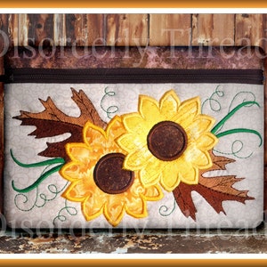 May include: A white zippered pouch with an embroidered design of two yellow sunflowers with brown centers and green leaves on a white background.