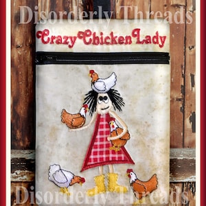 May include: A beige fabric zippered pouch with a black zipper and a black handle. The pouch has an embroidered image of a woman with a red and white checked dress holding chickens. The text "Crazy Chicken Lady" is embroidered on the pouch.