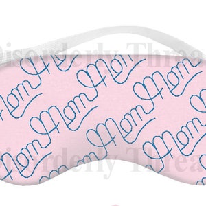 Può includere: Una maschera per dormire rosa con un elastico bianco. La maschera è ricoperta da un motivo ripetuto della parola "Mamma" scritta in corsivo blu.