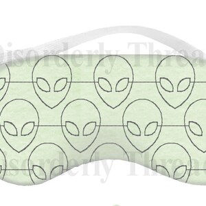 Può includere: Una maschera per dormire verde chiaro con un motivo ripetuto di volti alieni grigi. La maschera ha un cinturino elastico.