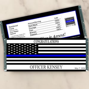 May include: A blue and white American flag with a thin blue line across the middle. The flag is on a black background with the text "Congratulations" and "Give it Arrest!" in white. The text "Officer Kensey" and "May 7, 2024" are also on the black background. The text "Integrity, Courage, Honor" is in a small box with a blue and white American flag in the background.