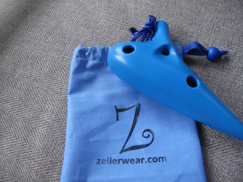 May include: A blue plastic ocarina with a drawstring bag. The bag has a black "Z" and the text "zellerwear.com" printed on it.