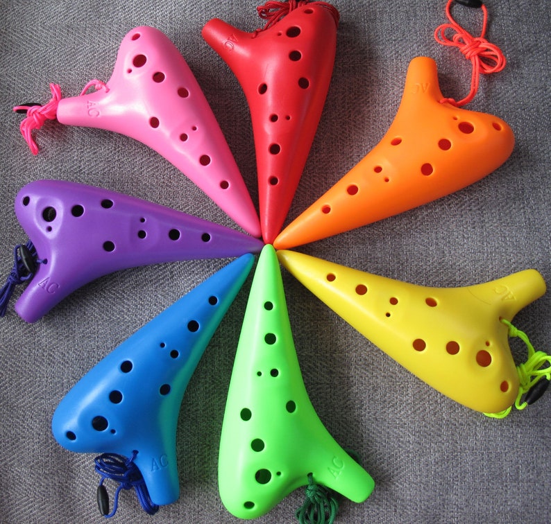May include: A set of seven colorful ocarinas, each with a different color and a string attached. The ocarinas are arranged in a circle, with the tips of each ocarina pointing towards the center of the circle.