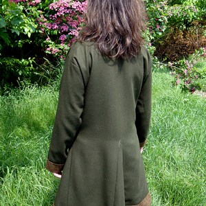 May include: A dark green long-sleeved jacket with a brown trim. The jacket has a long, flowing back and is made of a soft, comfortable fabric.