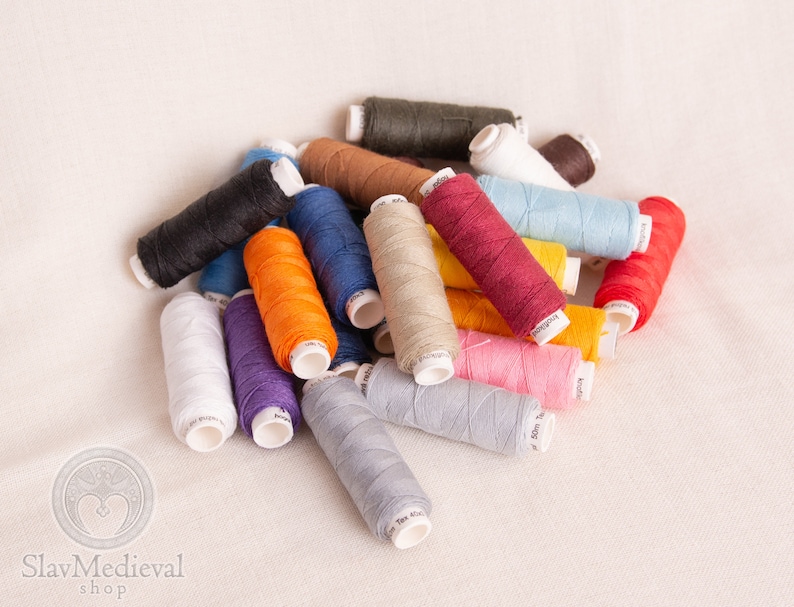May include: A collection of colorful spools of thread in various shades of red, orange, yellow, green, blue, purple, pink, brown, black, and white.
