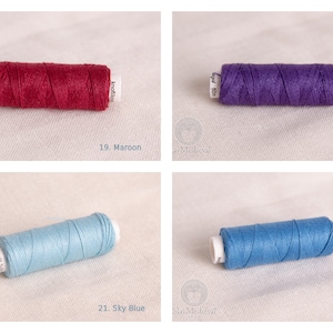May include: Four spools of thread in different colors: maroon, purple, sky blue, and blue. The spools are labeled with numbers 19, 20, 21, and 22.