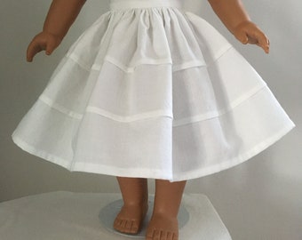 May include: A white cotton doll skirt with multiple layers and a gathered waistband.