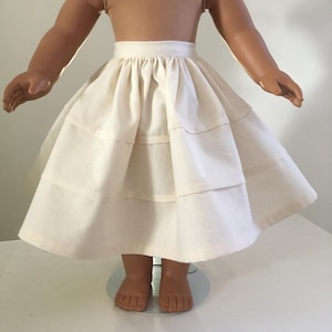 Puede incluir: Una falda de muñeca de algodón blanco con múltiples capas y una cintura fruncida.