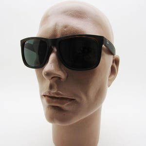 Puede incluir: Gafas de sol cuadradas negras con lentes oscuras. Las gafas de sol tienen un patr&oacute;n de carey marr&oacute;n en la montura interior y las patillas. El logotipo de Ray-Ban es visible en la patilla derecha. Las gafas se muestran en una cabeza de maniqu&iacute;.