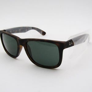 Puede incluir: Gafas de sol marrones y negras con lentes verde oscuro. Las gafas tienen una montura cuadrada y un patr&oacute;n de carey en las patillas. El logotipo de Ray-Ban es visible en la patilla.