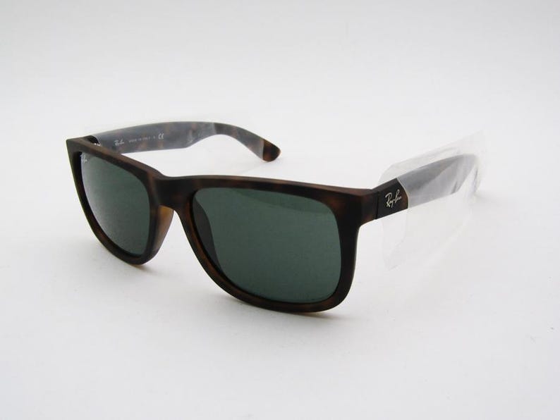 Puede incluir: Gafas de sol marrones y negras con lentes verde oscuro. Las gafas tienen una montura cuadrada y un patr&oacute;n de carey en las patillas. El logotipo de Ray-Ban es visible en la patilla.