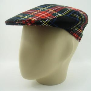 May include: A traditional flat cap featuring a tartan design in red, green, yellow, blue, and white, set against a black backdrop. The cap is shown on a mannequin head. This hat is a common accessory for casual outfits.