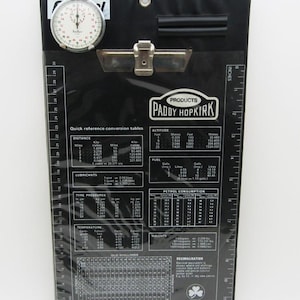 Może przedstawiać: Biały ceramiczny kubek z czarnym uchwytem i napisem "But First, Coffee" pogrubioną, czarną czcionką. Kubek stoi na białej powierzchni, podkreślając jego czysty design.