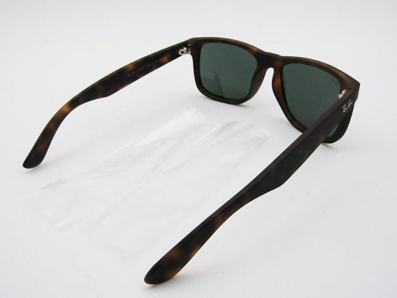 Puede incluir: Gafas de sol con estampado de carey y lentes verde oscuro. Las gafas tienen una montura rectangular cl&aacute;sica. Las patillas est&aacute;n abiertas, revelando el interior. El logotipo de Ray-Ban es visible en la patilla.