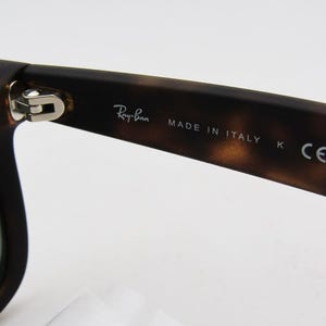 Puede incluir: Primer plano de gafas de sol con un patr&oacute;n de carey marr&oacute;n. El logotipo de Ray-Ban es visible en la patilla, junto con el texto "MADE IN ITALY" y "K CE". Las gafas de sol tienen un dise&ntilde;o cl&aacute;sico.