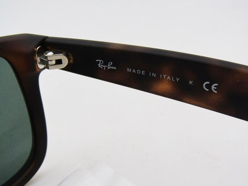 Puede incluir: Primer plano de gafas de sol con un patr&oacute;n de carey marr&oacute;n. El logotipo de Ray-Ban es visible en la patilla, junto con el texto "MADE IN ITALY" y "K CE". Las gafas de sol tienen un dise&ntilde;o cl&aacute;sico.