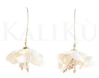 May include: A pair of white flower-shaped earrings with gold accents and crystal beads hanging from the center.