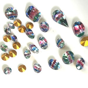 Może przedstawiać: Asortyment iryzujących, fasetowanych kryształów i złotych, fasetowanych, okrągłych ozdób. Kryształy mają różne kształty, w tym okrągłe, owalne i łezki, z odcieniami różu, błękitu i zieleni. Złote ozdoby są małe i płaskie.