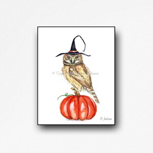 May include: A watercolor painting of a brown owl wearing a black witch hat with an orange brim. The owl is perched on top of a red pumpkin.