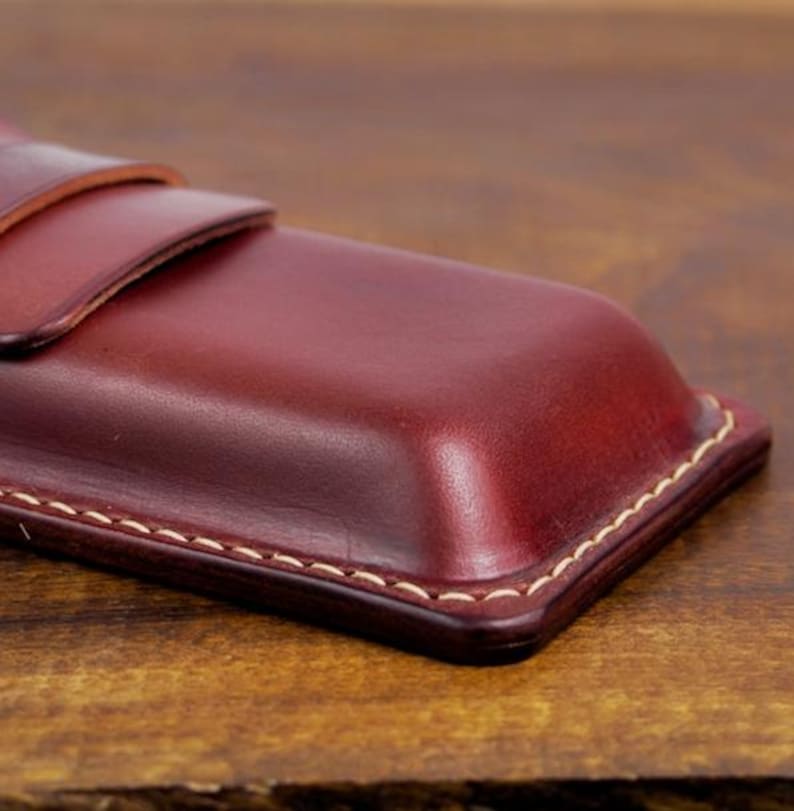 Leather pencil case with compartment in mahogany color lying on a wooden board