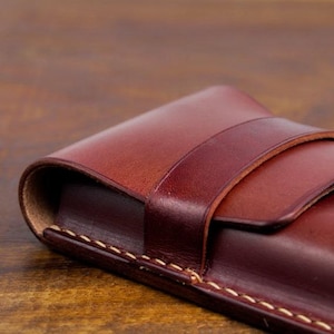 Leather pencil case with compartment in mahogany color lying on a wooden board