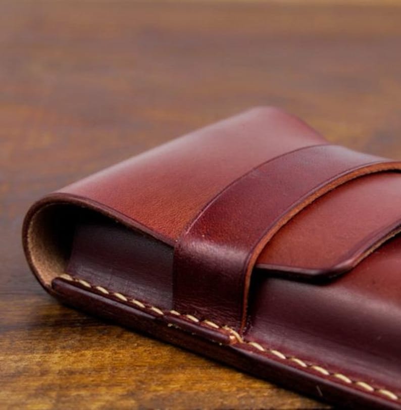 Leather pencil case with compartment in mahogany color lying on a wooden board