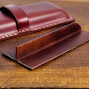 Leather pencil case with compartment in mahogany color lying on a wooden board