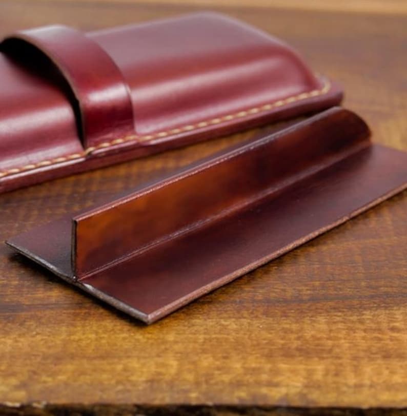 Leather pencil case with compartment in mahogany color lying on a wooden board