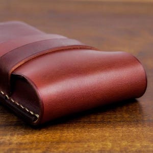 Leather pencil case with compartment in mahogany color lying on a wooden board