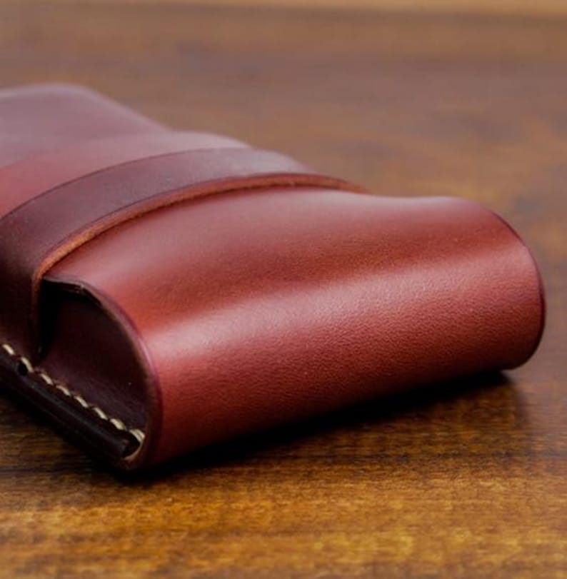 Leather pencil case with compartment in mahogany color lying on a wooden board
