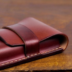 Leather pencil case with compartment in mahogany color lying on a wooden board