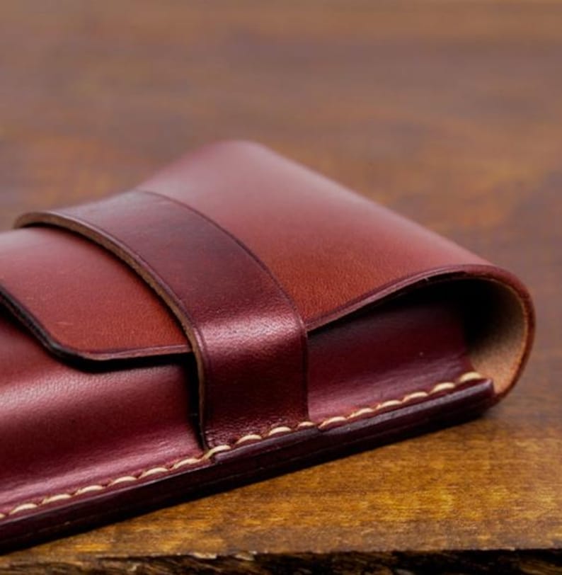 Leather pencil case with compartment in mahogany color lying on a wooden board