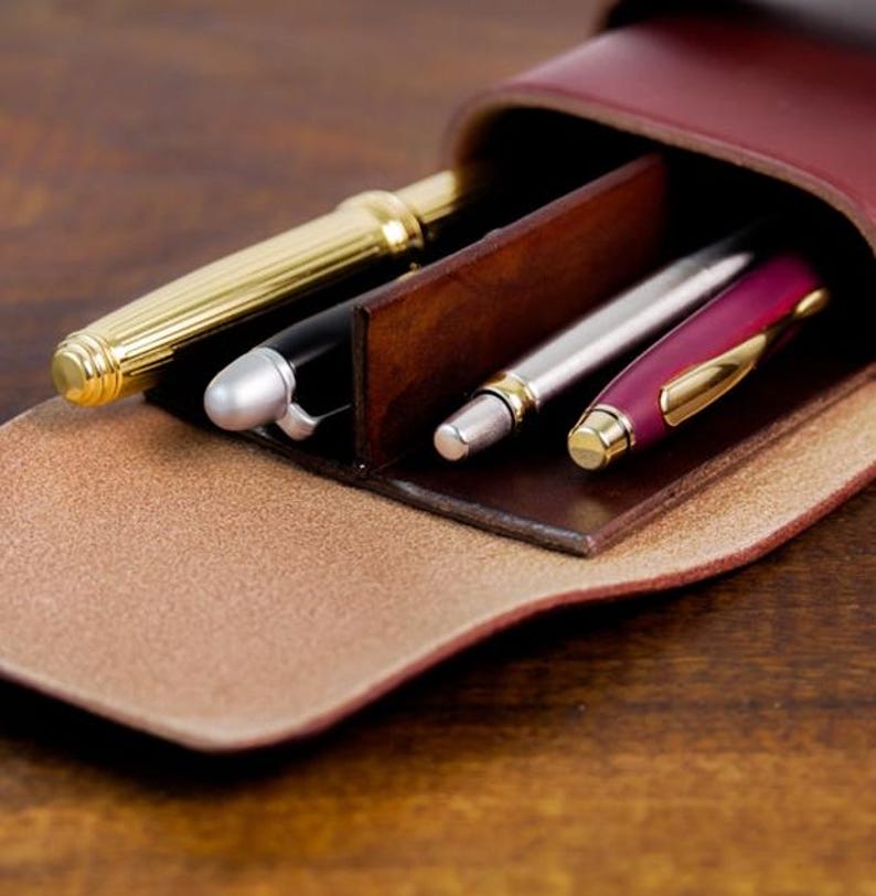 Leather pencil case with compartment in mahogany color lying on a wooden board