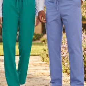 May include: Two pairs of scrub pants, one in solid teal and one in solid light blue. Both pairs feature an elastic waistband with a matching drawstring tie, straight legs, and side pockets, paired with white sneakers and long-sleeved white shirts.