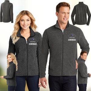 Puede incluir: Una chaqueta de forro polar gris oscuro con cierre de cremallera y cuello alto. La chaqueta tiene un pequeño logotipo bordado en el pecho izquierdo que dice "Marvelous Printing" y "YOUR LOGO OR TEXT".