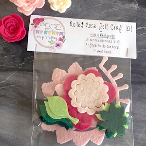 May include: A craft kit for making rolled felt roses. The kit includes three different sizes of felt roses, three flower backs, and seven small leaves. The kit is packaged in a clear plastic bag with a label that reads "Rolled Rose Felt Craft Kit".