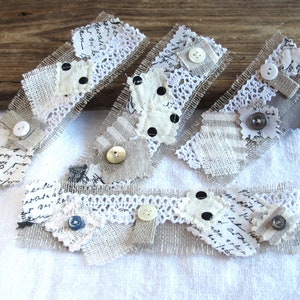 May include: Five handmade fabric bookmarks with a rustic, vintage aesthetic. Each bookmark features a combination of lace, burlap, and patterned fabric with buttons and other embellishments.