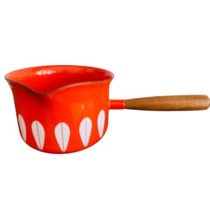 May include: A bright orange saucepan with a wooden handle. The pan features a white teardrop pattern around the base. The handle is a light brown color. The saucepan is designed for cooking.