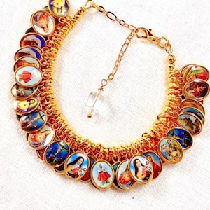 May include: A gold charm bracelet with a variety of colorful religious images. The bracelet has a clear crystal charm hanging from it.