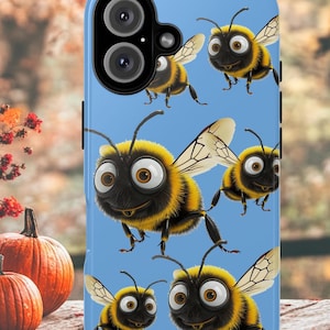 May include: A light blue phone case featuring a cartoon illustration of several bees with yellow and black stripes, large eyes, and wings. The bees are arranged on the case against a light blue background.