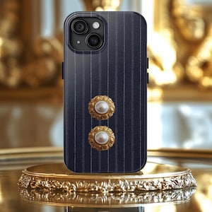 May include: A navy blue phone case with a pinstripe pattern and two gold and pearl embellishments.